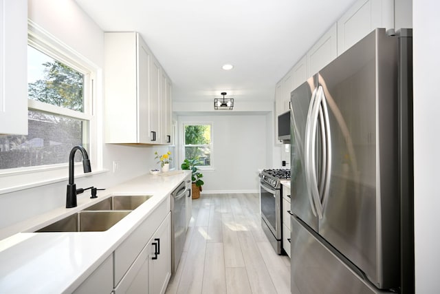 kitchen featuring stainless steel appliances, white cabinetry, sink, and light hardwood / wood-style flooring