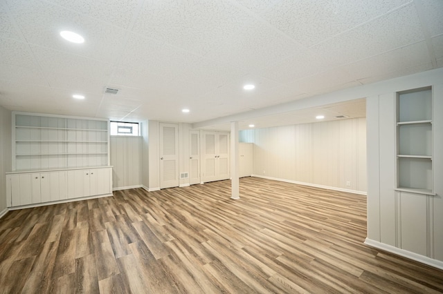 basement featuring built in shelves and light hardwood / wood-style flooring