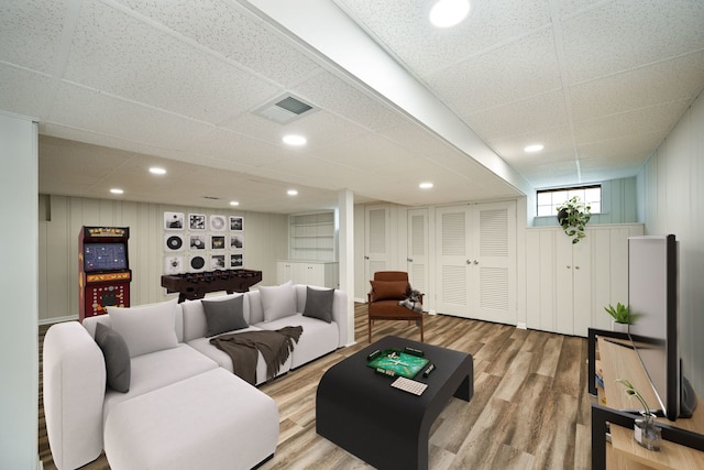 living room featuring a drop ceiling and light wood-type flooring