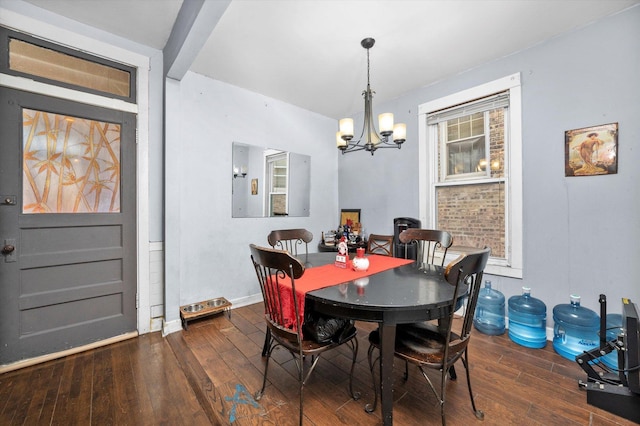 dining area with dark wood-type flooring and an inviting chandelier