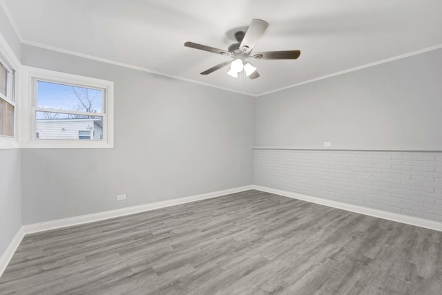 empty room featuring ceiling fan, ornamental molding, brick wall, and hardwood / wood-style flooring