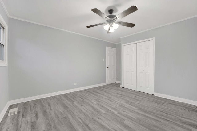 unfurnished bedroom with light wood-type flooring, a closet, ceiling fan, and ornamental molding