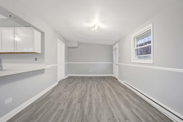 empty room with light hardwood / wood-style flooring and baseboard heating