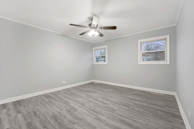 empty room featuring ceiling fan, plenty of natural light, wood-type flooring, and ornamental molding