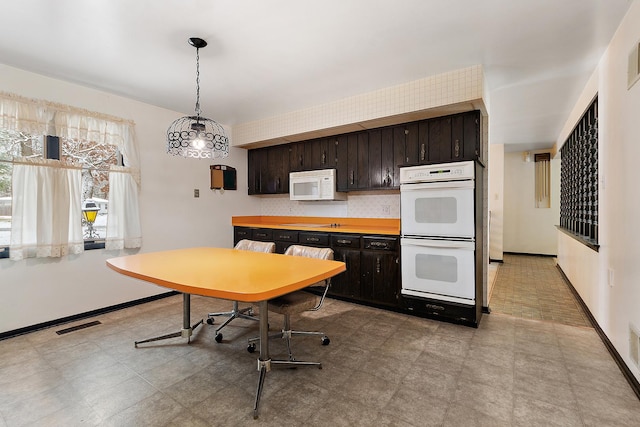 kitchen with dark brown cabinetry, pendant lighting, and white appliances