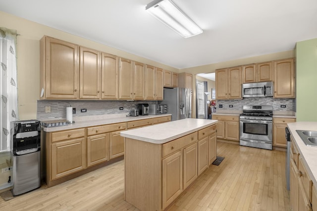 kitchen with a kitchen island, light wood-type flooring, stainless steel appliances, and tasteful backsplash