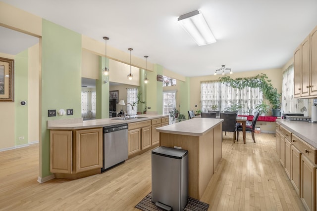 kitchen featuring stainless steel dishwasher, a kitchen island, hanging light fixtures, and light hardwood / wood-style flooring