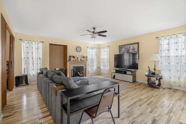 living room with ceiling fan, light wood-type flooring, and a wealth of natural light