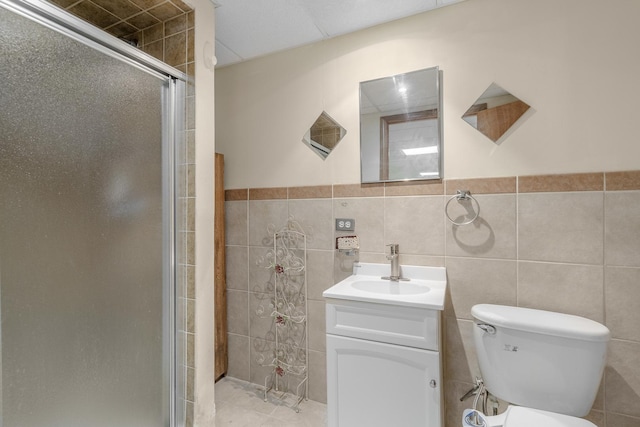 bathroom featuring vanity, tile patterned flooring, toilet, tile walls, and an enclosed shower