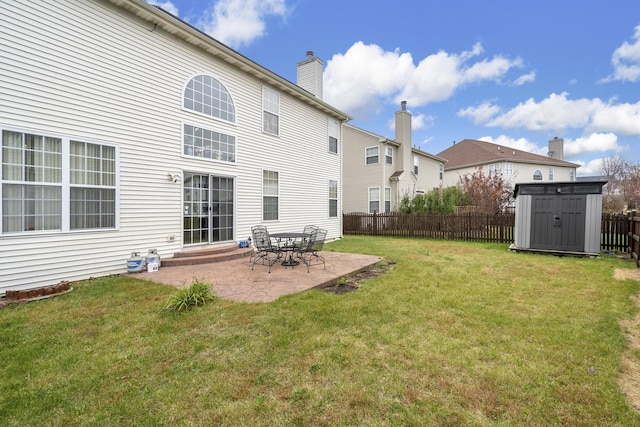 rear view of house with a lawn, a patio, and a shed