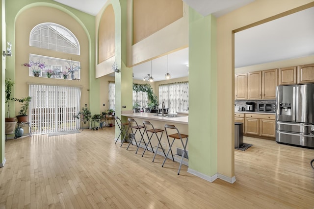 kitchen with stainless steel fridge, light brown cabinets, and light hardwood / wood-style floors