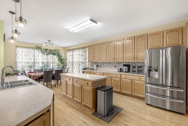 kitchen featuring stainless steel fridge, sink, a center island, light hardwood / wood-style floors, and hanging light fixtures