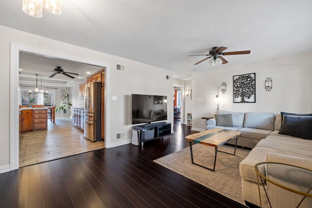 living room featuring dark hardwood / wood-style flooring and ceiling fan with notable chandelier