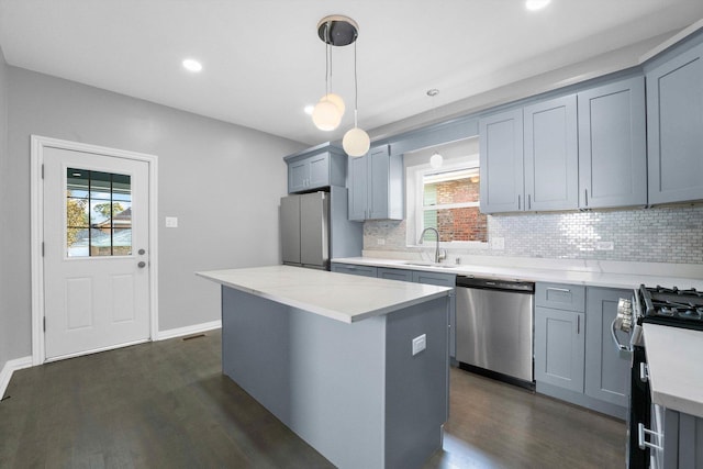 kitchen with dark hardwood / wood-style floors, a center island, hanging light fixtures, and appliances with stainless steel finishes