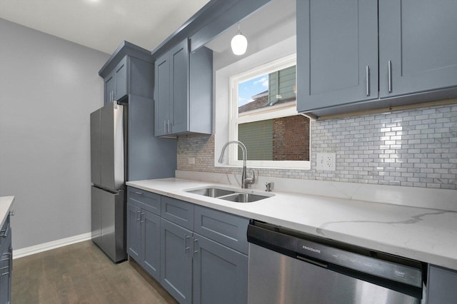 kitchen featuring light stone countertops, sink, dark wood-type flooring, stainless steel dishwasher, and decorative backsplash