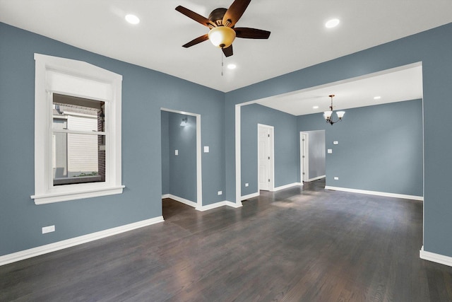 empty room featuring ceiling fan with notable chandelier and dark hardwood / wood-style flooring