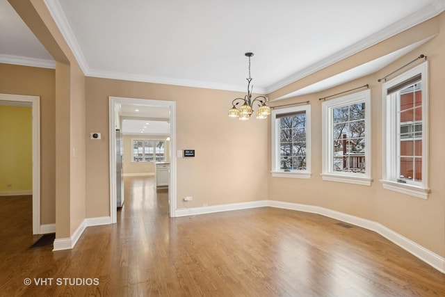 unfurnished dining area with an inviting chandelier, crown molding, and hardwood / wood-style flooring