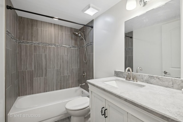 full bathroom featuring tiled shower / bath combo, vanity, and toilet