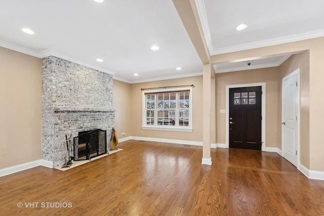 entrance foyer with ornamental molding, a brick fireplace, and wood-type flooring