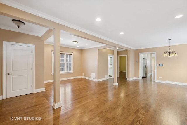 unfurnished living room featuring hardwood / wood-style flooring, crown molding, and a chandelier