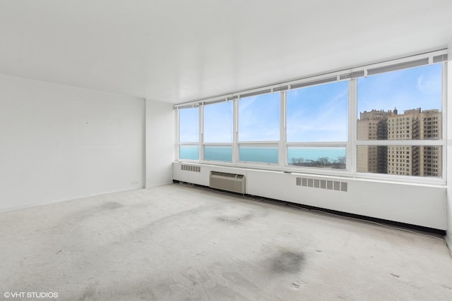 carpeted empty room featuring a wall mounted air conditioner, a water view, and a wealth of natural light