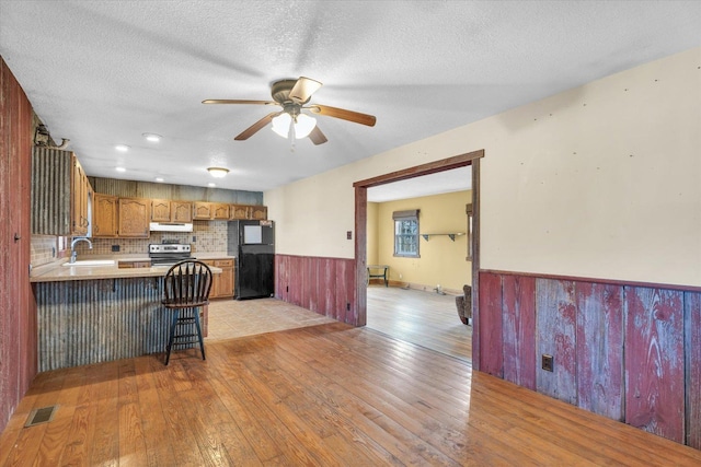 kitchen featuring sink, a breakfast bar area, black fridge, kitchen peninsula, and stainless steel electric stove