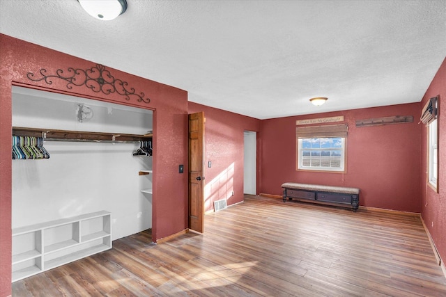 unfurnished bedroom with a textured ceiling, hardwood / wood-style flooring, and a closet