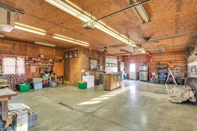 garage with water heater, wooden walls, refrigerator, and a garage door opener