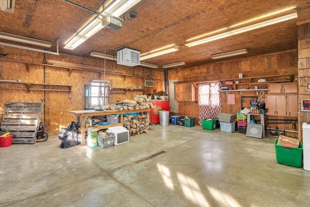 garage with a workshop area, a garage door opener, and wooden walls