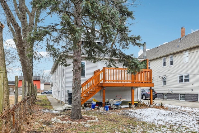 snow covered rear of property with a wooden deck