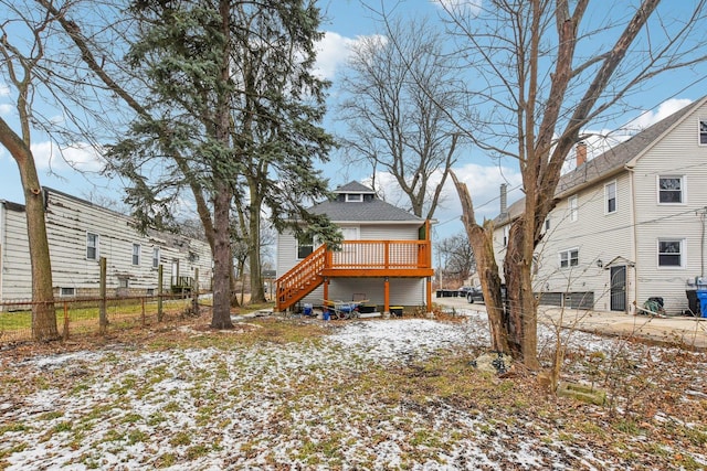 snow covered back of property with a deck