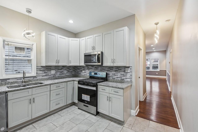 kitchen with appliances with stainless steel finishes, light stone counters, light tile patterned floors, and sink