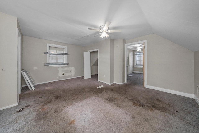 bonus room with dark carpet, plenty of natural light, and lofted ceiling