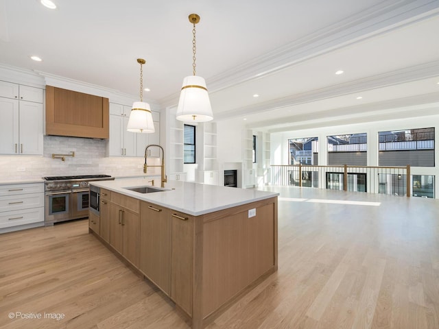 kitchen with sink, double oven range, pendant lighting, white cabinets, and light wood-type flooring