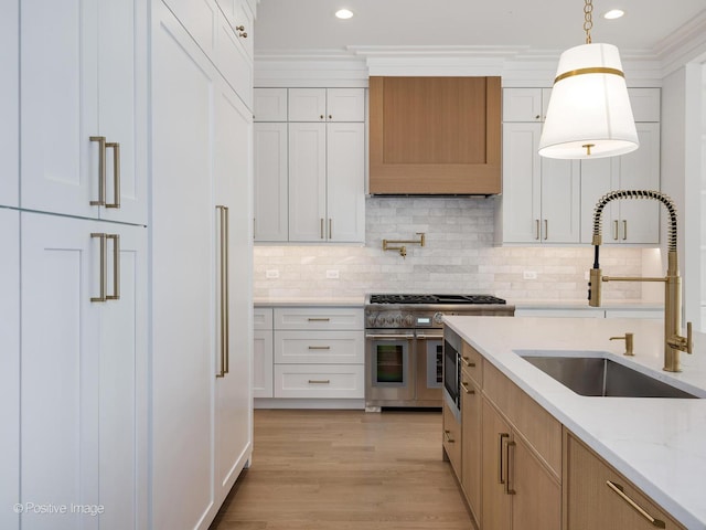 kitchen with sink, light stone counters, double oven range, light hardwood / wood-style floors, and white cabinets