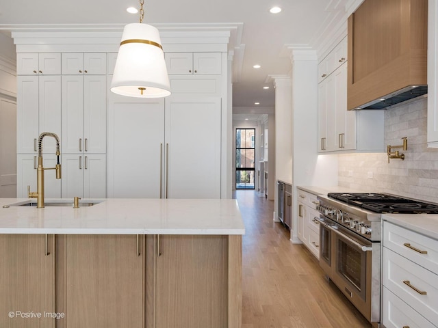 kitchen featuring light wood-type flooring, sink, range with two ovens, white cabinetry, and hanging light fixtures