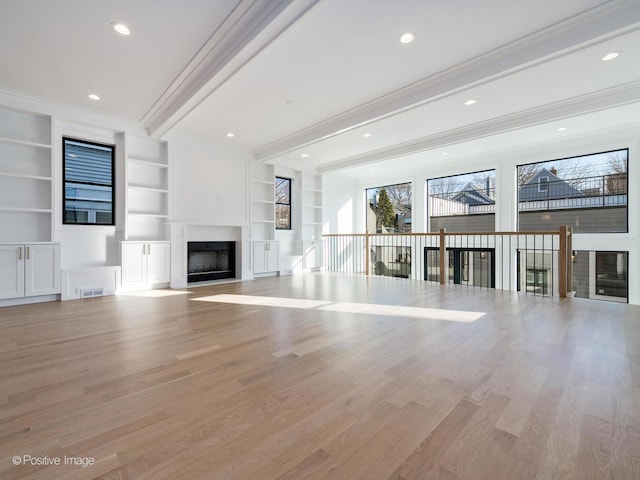 unfurnished living room with beam ceiling, light hardwood / wood-style flooring, built in features, and crown molding