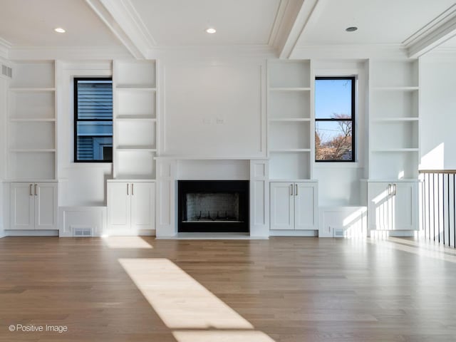 unfurnished living room with built in features, light hardwood / wood-style flooring, and ornamental molding