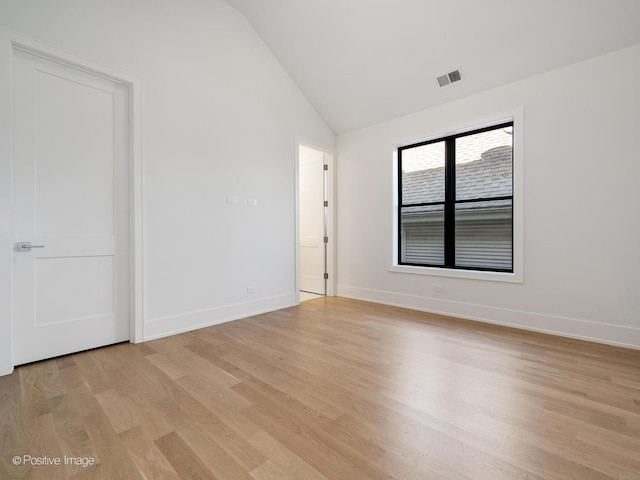 empty room with lofted ceiling and light hardwood / wood-style flooring