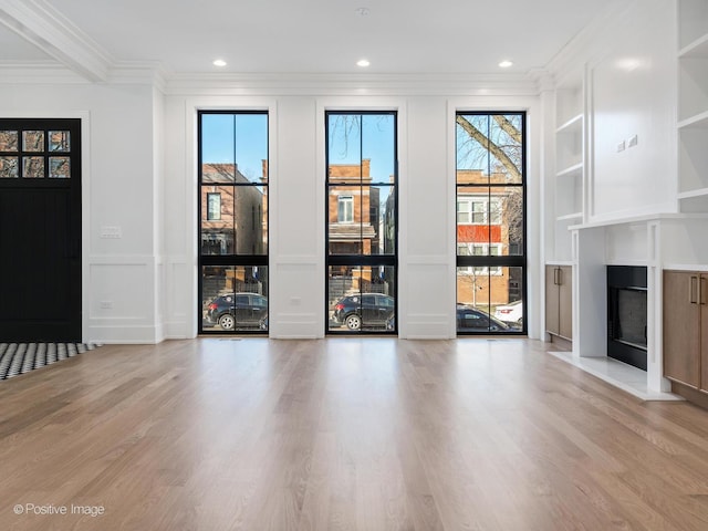 unfurnished living room featuring hardwood / wood-style floors, crown molding, and a healthy amount of sunlight