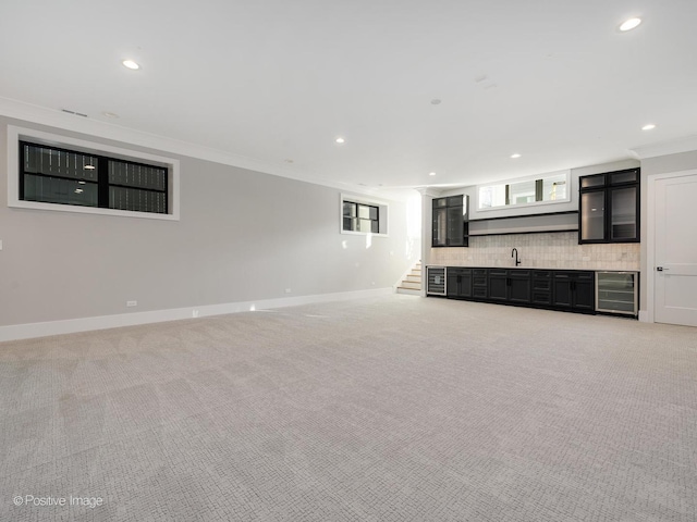 unfurnished living room featuring carpet, ornamental molding, sink, and beverage cooler