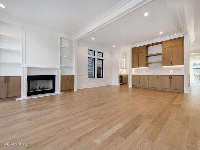 unfurnished living room featuring light hardwood / wood-style flooring, built in features, and ornamental molding