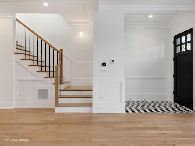 foyer entrance with ornamental molding and hardwood / wood-style flooring