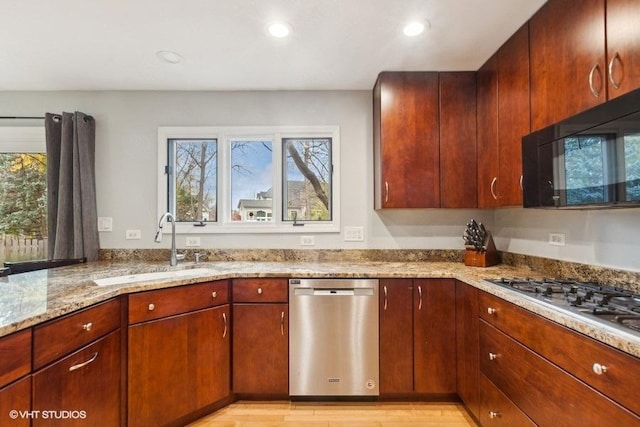 kitchen with light wood finished floors, appliances with stainless steel finishes, light stone counters, a sink, and recessed lighting