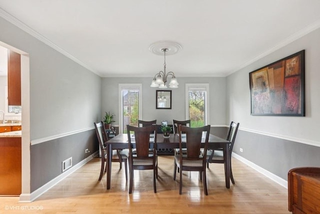 dining area with light wood-style floors, a chandelier, ornamental molding, and baseboards