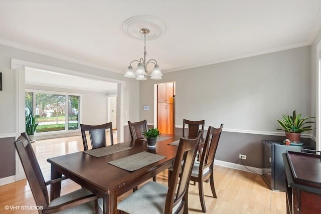 dining space with baseboards, a notable chandelier, crown molding, and light wood finished floors