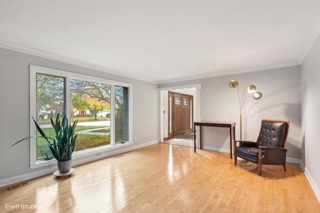 sitting room with ornamental molding, visible vents, light wood-style flooring, and baseboards