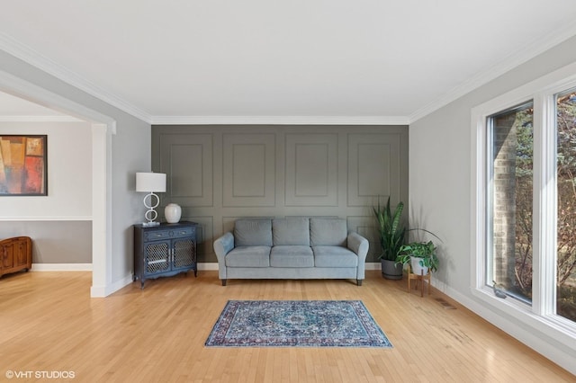 living room featuring light wood finished floors, ornamental molding, and baseboards