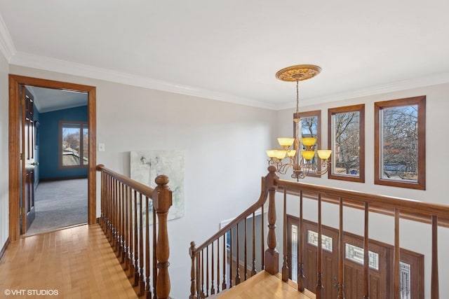 hall featuring ornamental molding, light wood-style floors, an upstairs landing, and a notable chandelier