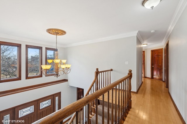 corridor featuring a chandelier, light wood finished floors, an upstairs landing, and baseboards